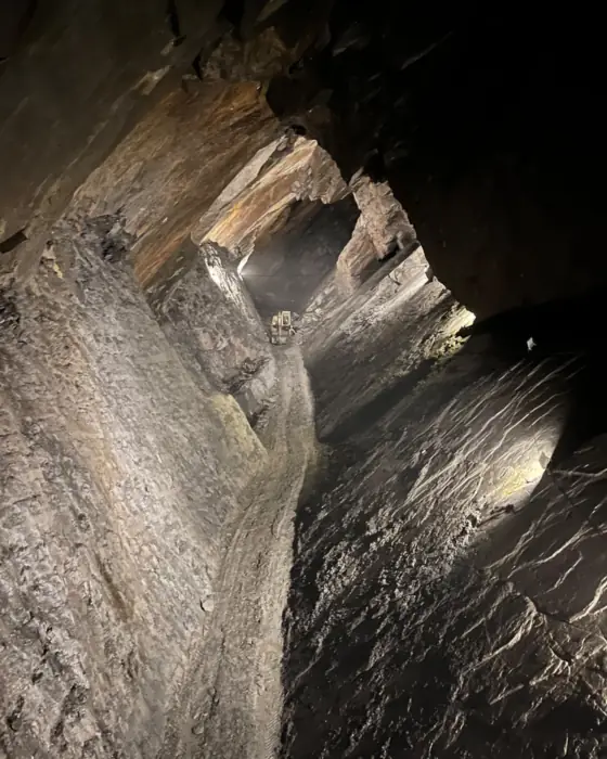 Vaste galerie souterraine éclairée, un engin de chantier minuscule au fond
